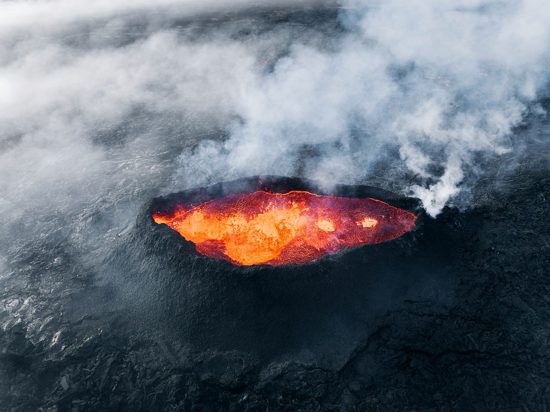 A bubbling volcanic crater with glowing orange lava and white smoke.