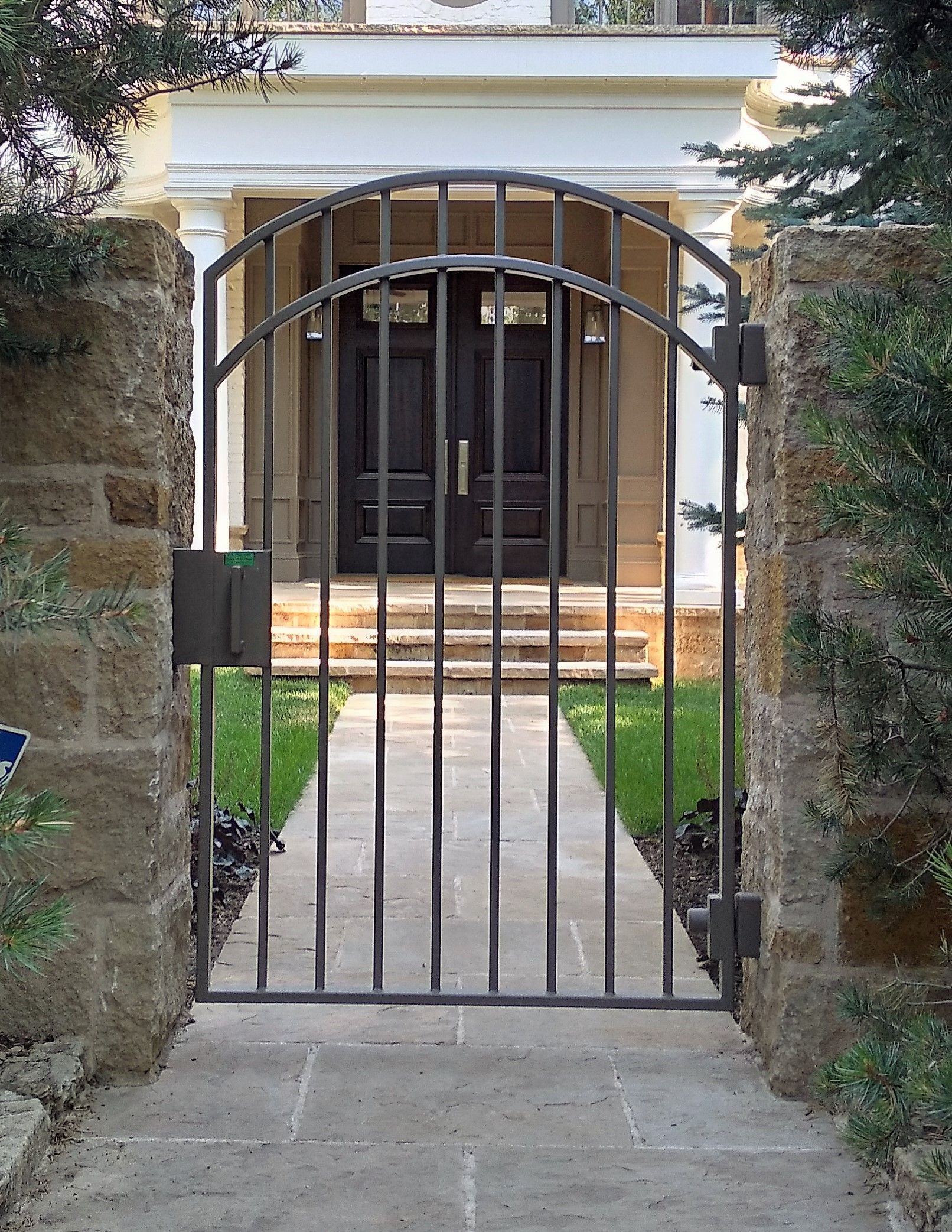 A wrought iron gate leads to the front door of a house