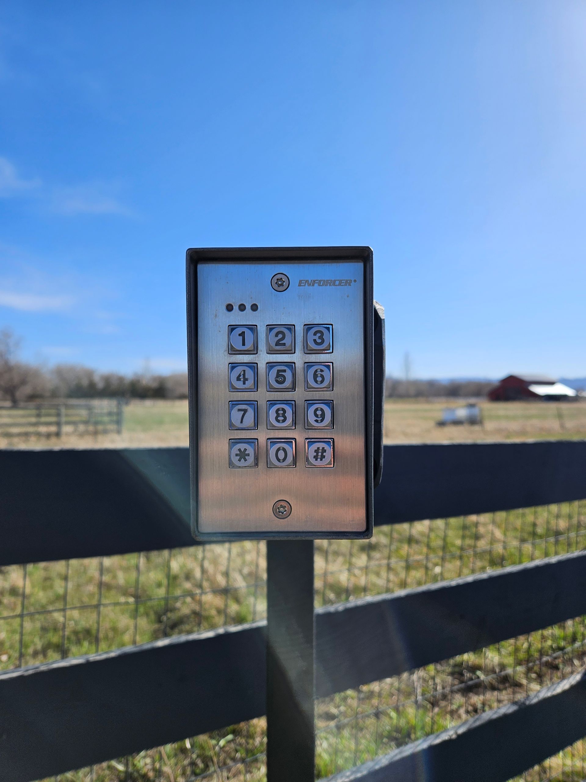 A keypad on a pole next to a fence