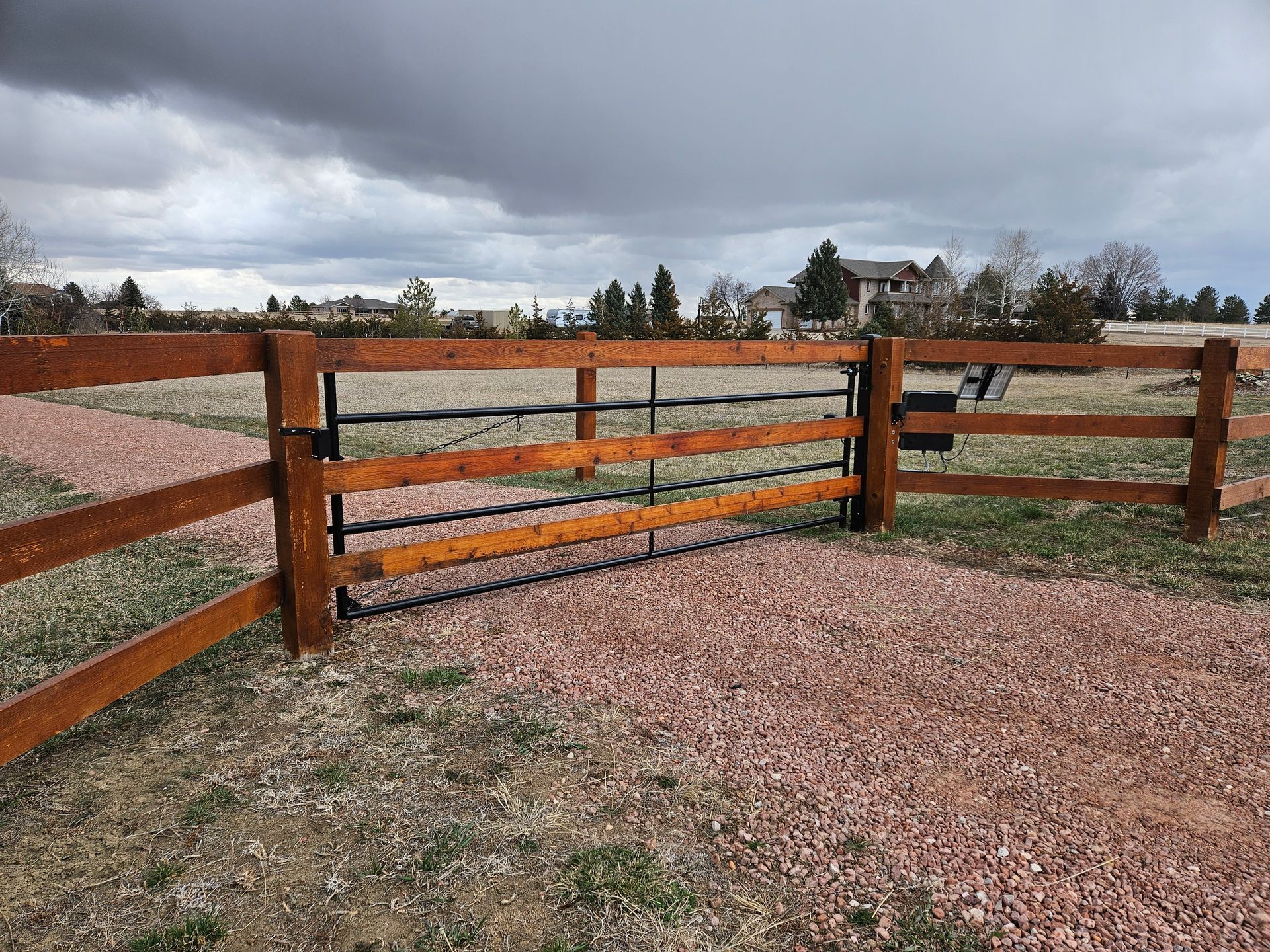 A wooden fence with a gate in the middle of a field.