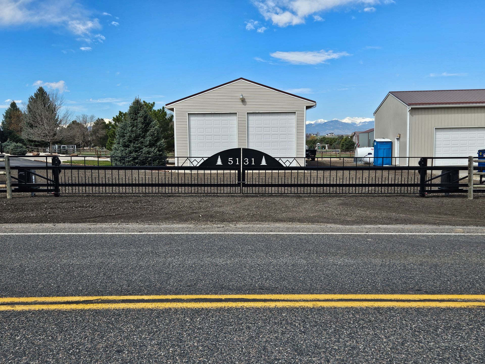 A fence along the side of a road with a garage in the background.