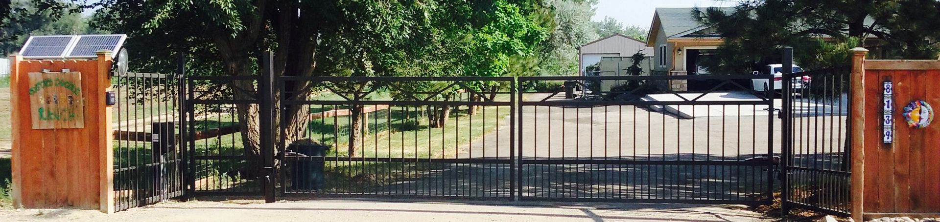 A metal gate with a wooden post in front of a house.