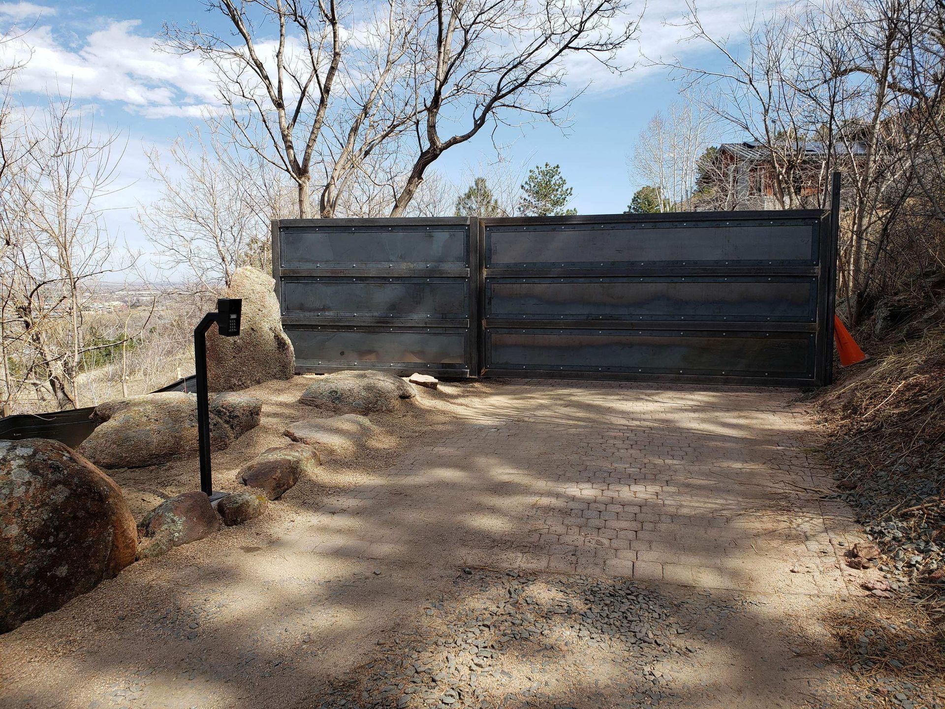 There is a gate in the middle of a dirt road.