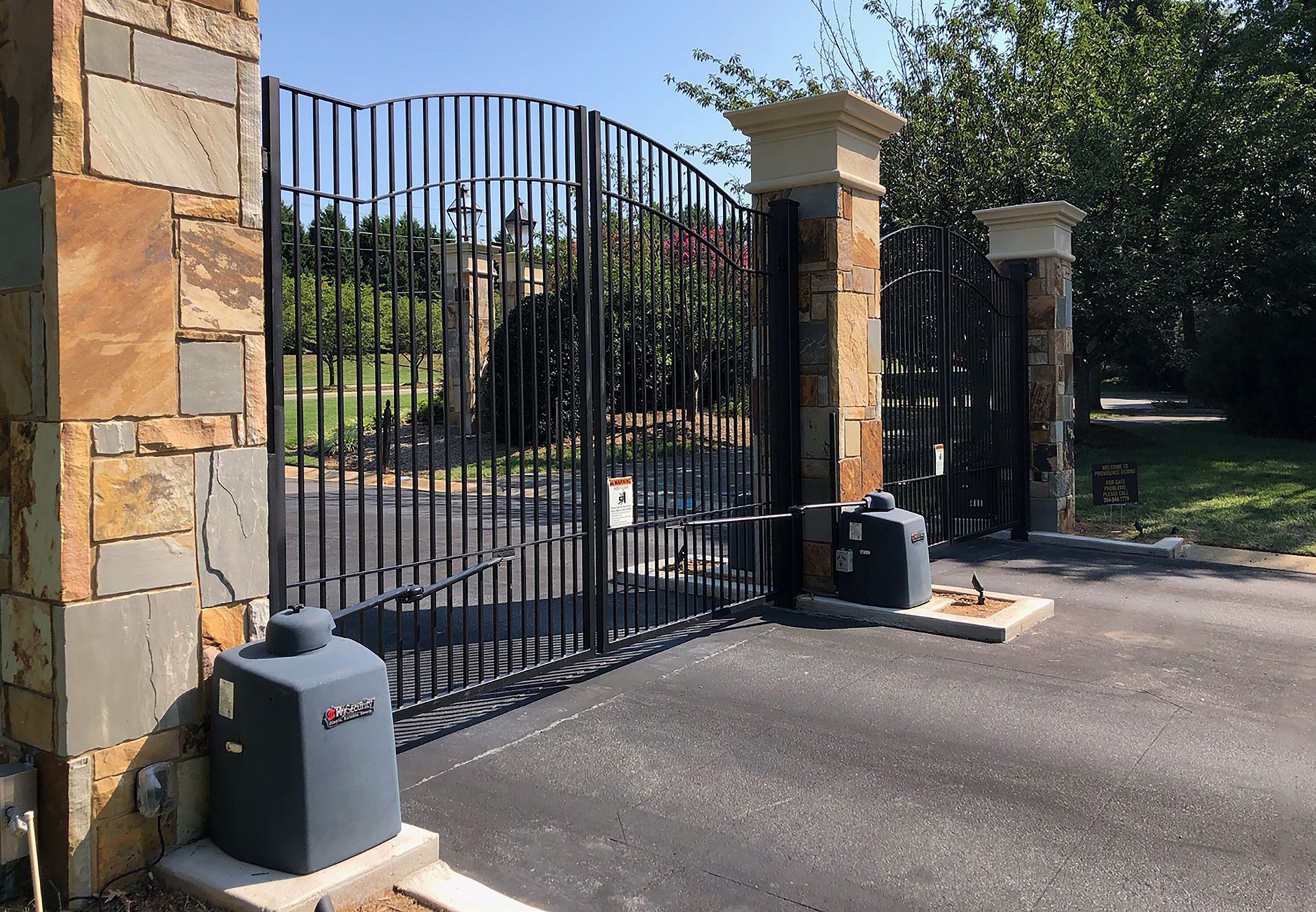 A wrought iron gate is surrounded by stone pillars.