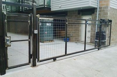 A chain link fence with a gate in front of a building.
