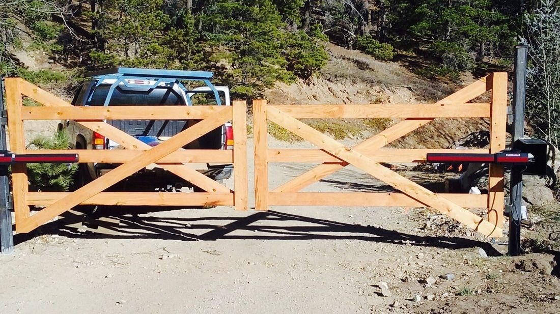 A truck is driving through a wooden gate on a dirt road.