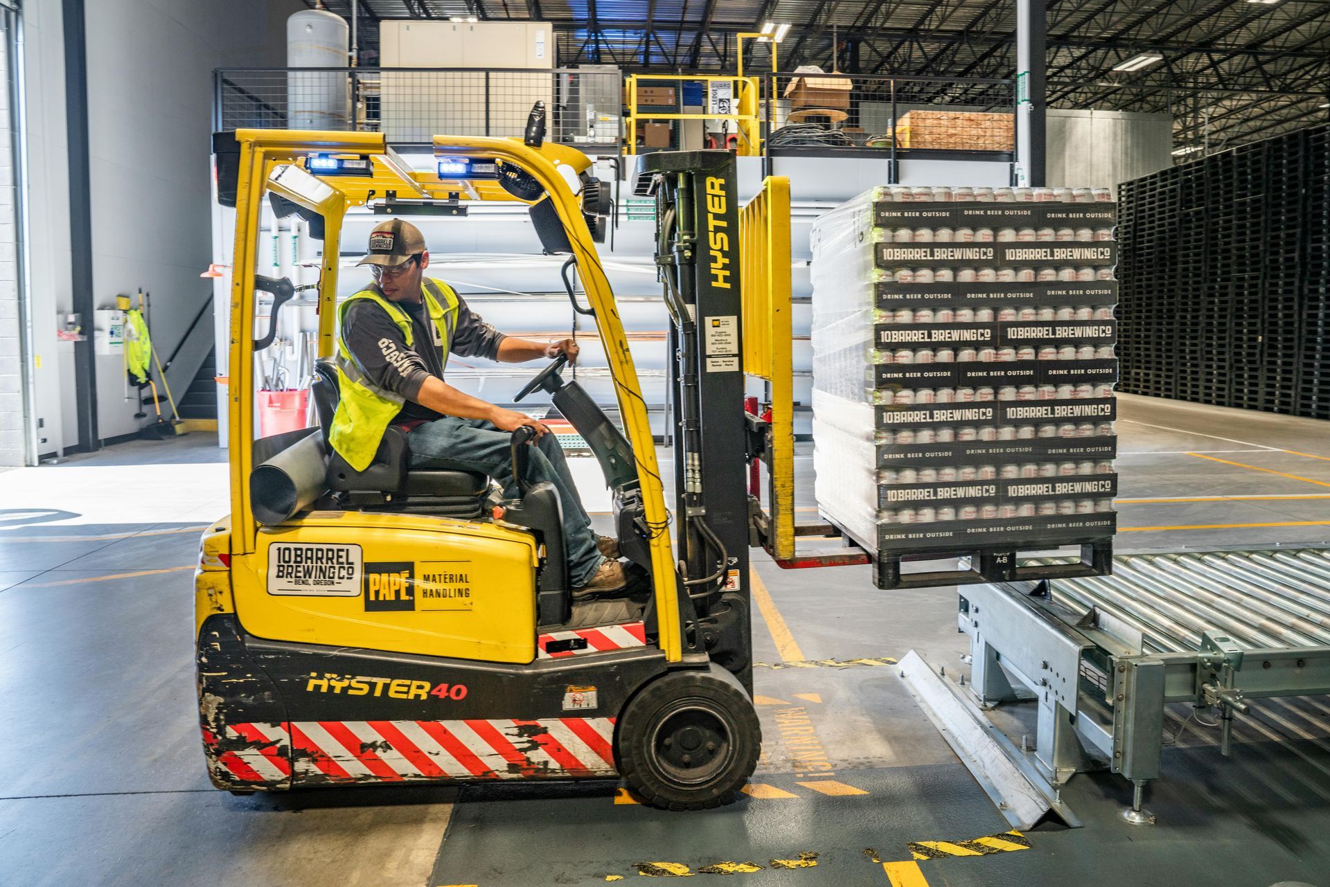 A man is driving a forklift in a warehouse.