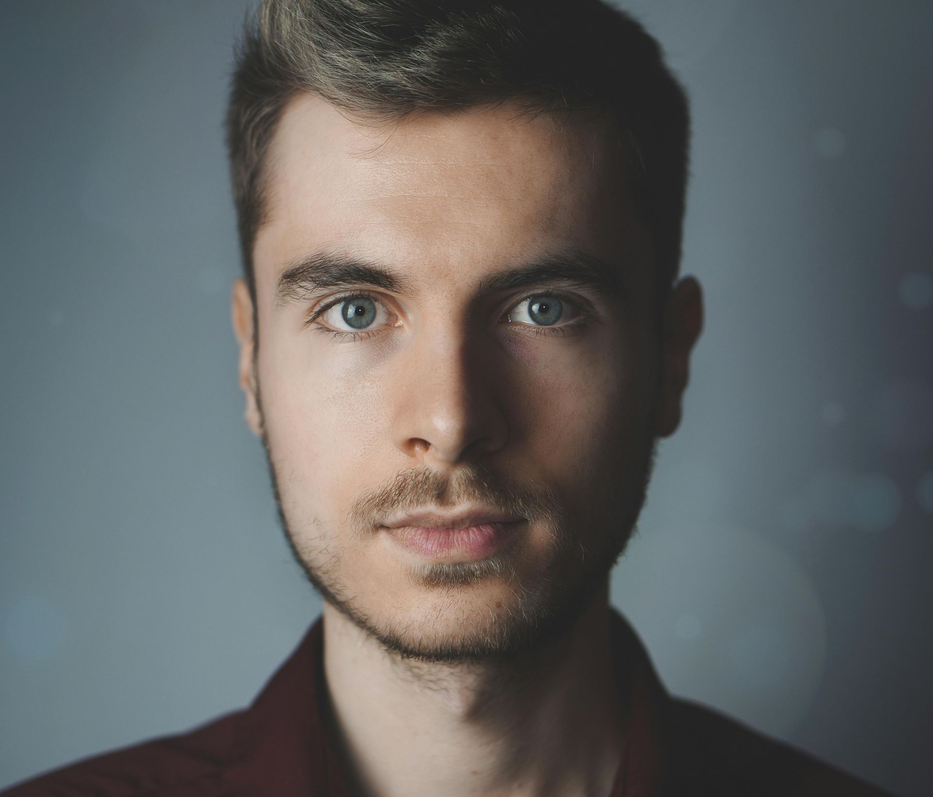 A close up of a man 's face with a beard and blue eyes.