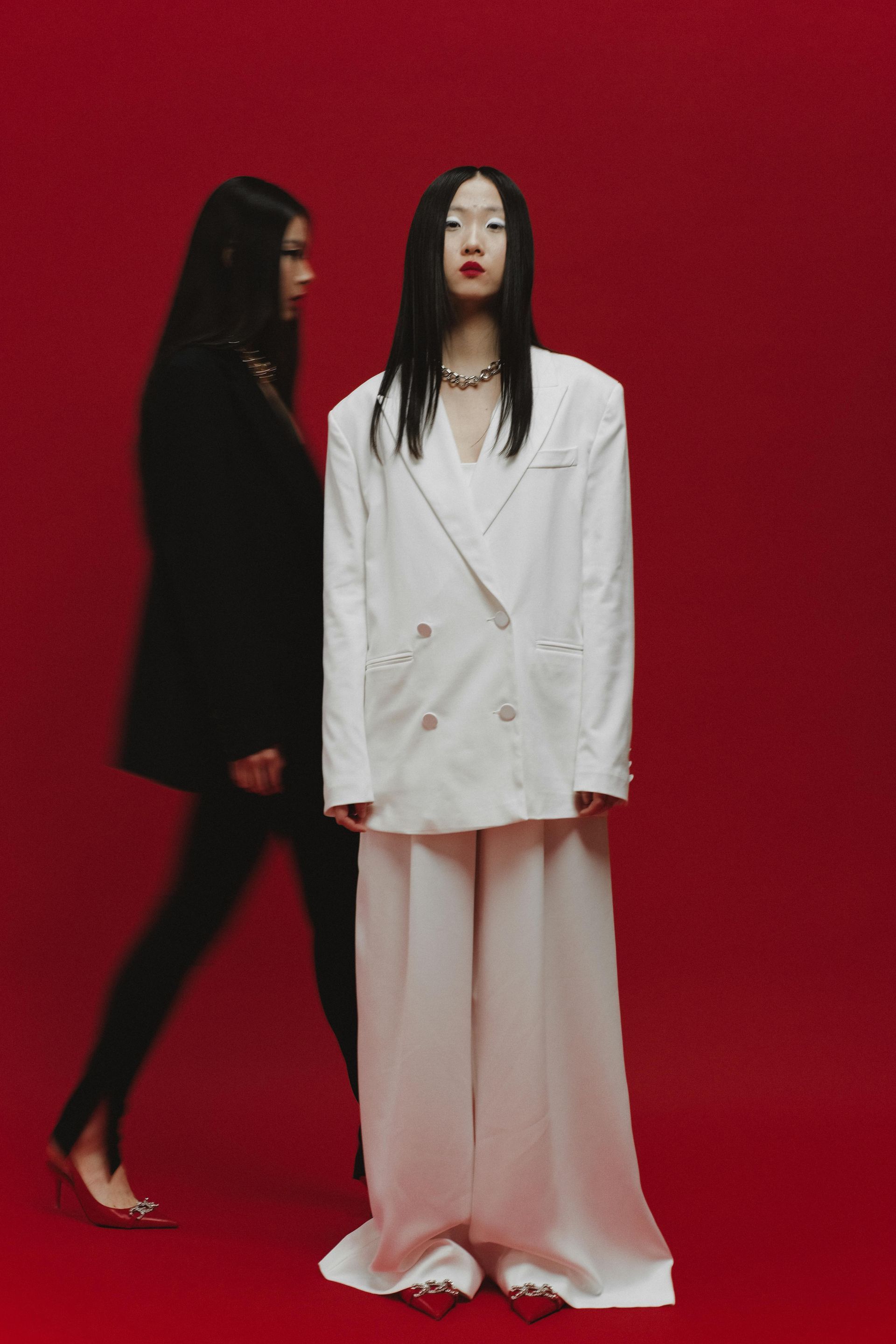 A woman in a white suit is standing next to another woman in a black suit.