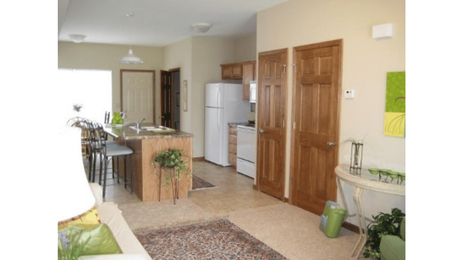 A living room with a refrigerator and a kitchen in the background