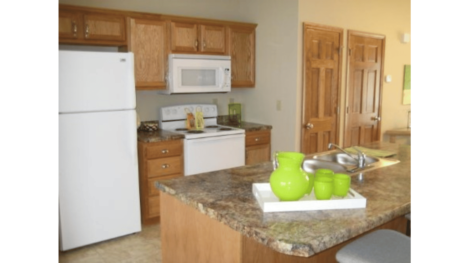 A kitchen with a white refrigerator , stove , microwave and sink.