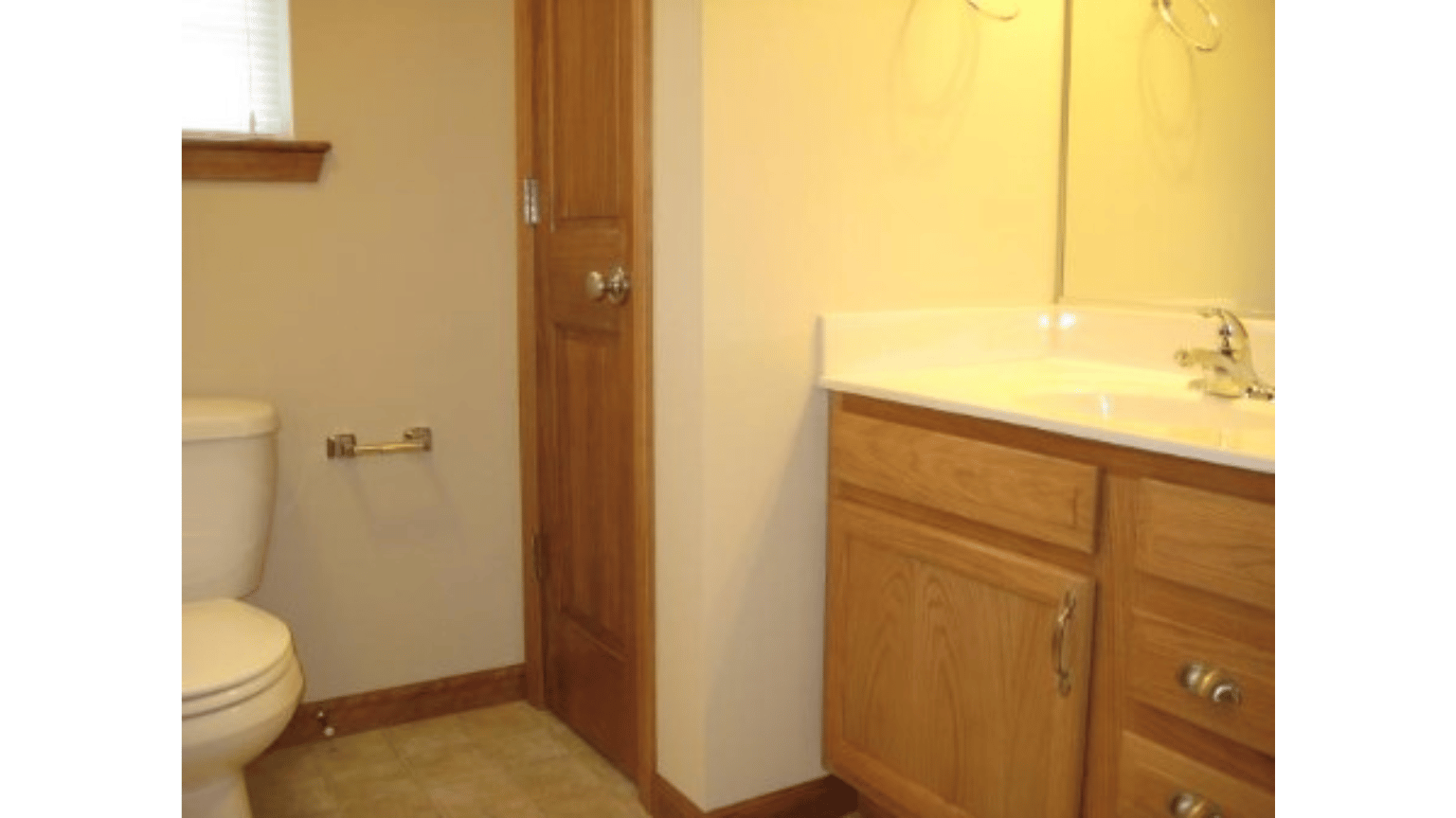 A bathroom with a toilet , sink and mirror.