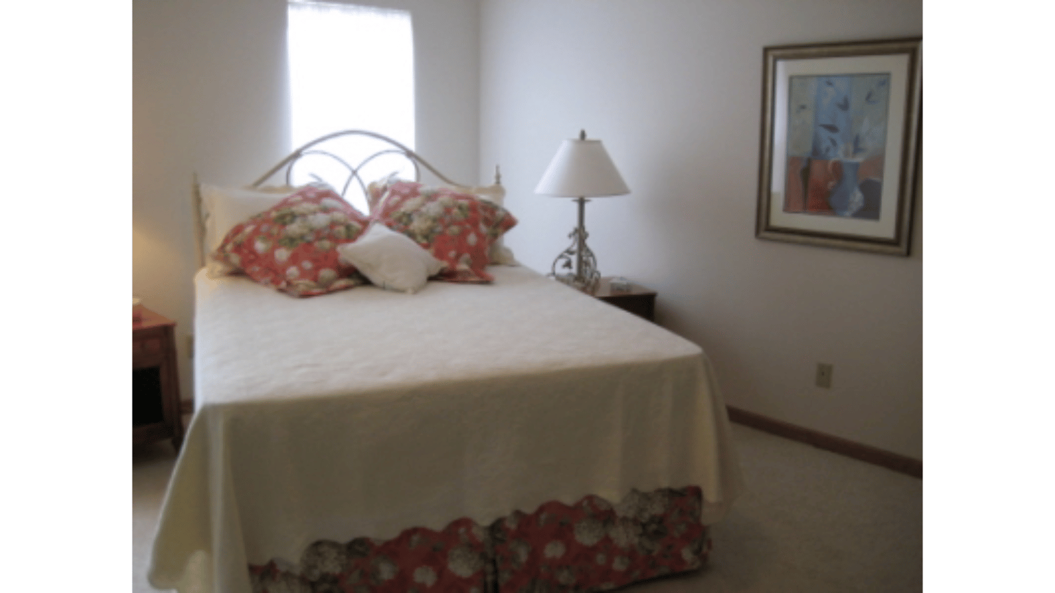 A bedroom with a large bed and a lamp