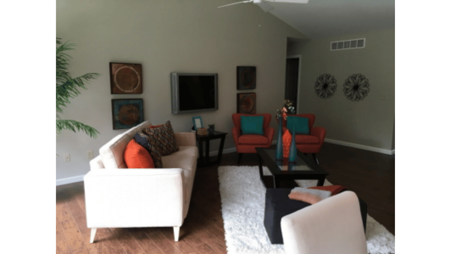 A living room with a couch , chairs , coffee table and television.