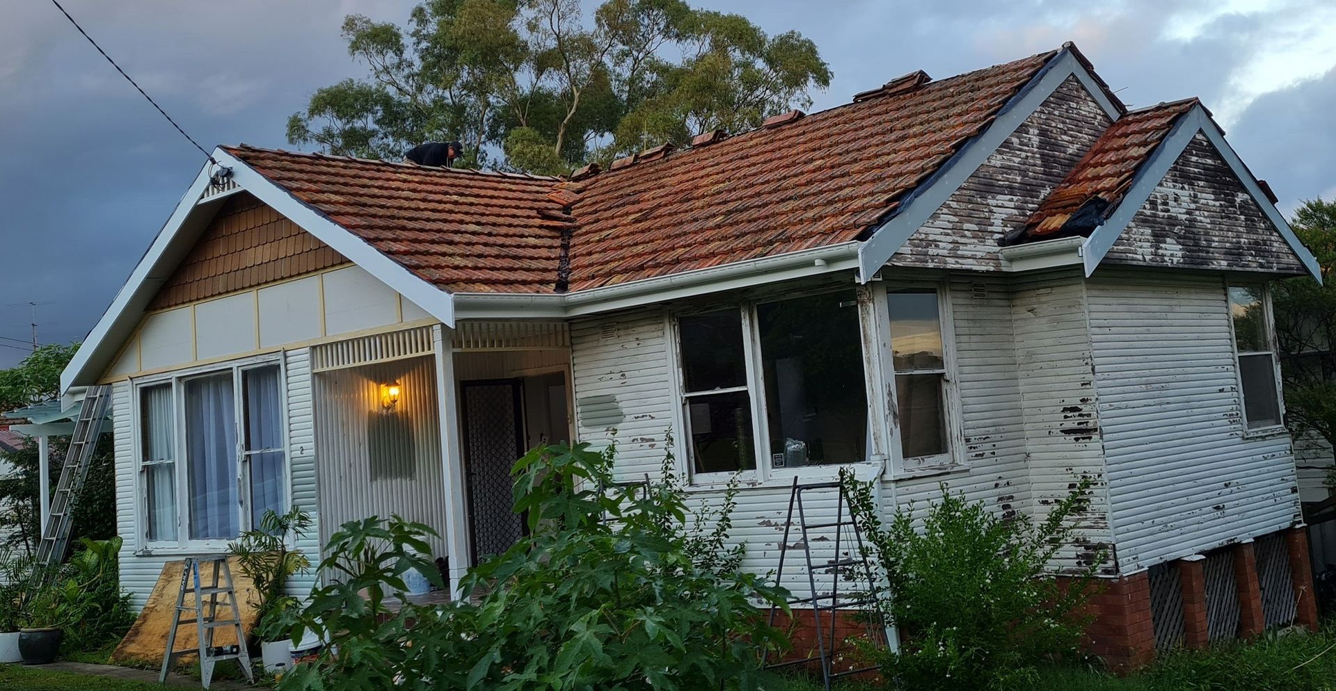 Dilapidated White House with Damaged Roof and Siding — Stan Painting Services In Hamilton, NSW