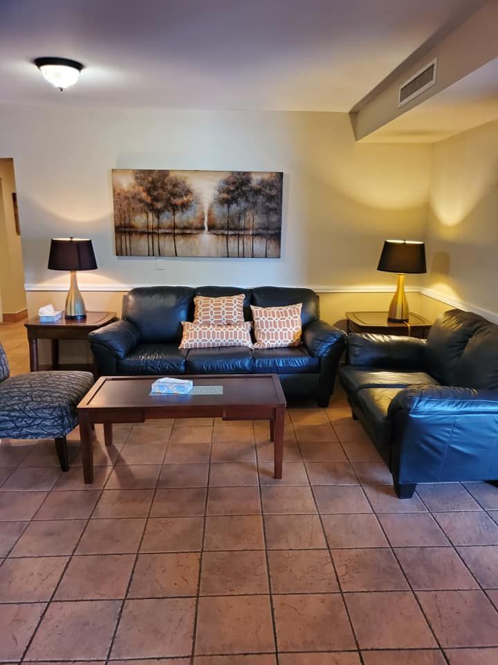 Living room with a leather sofa, arm chair, artwork, and lamps.
