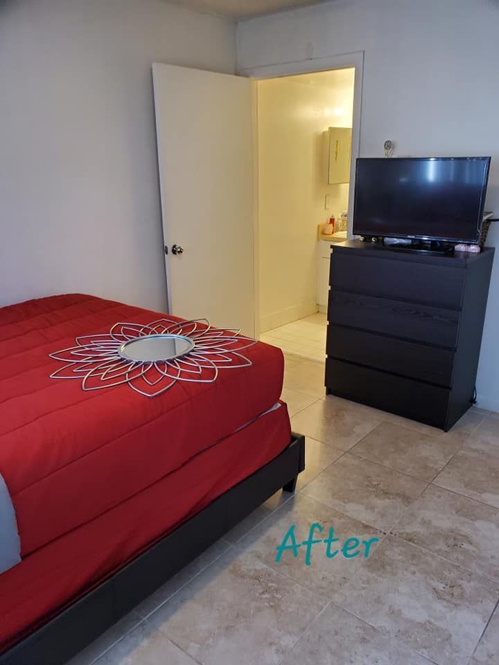 Bedroom with red bed, TV on black dresser, open door to bathroom.
