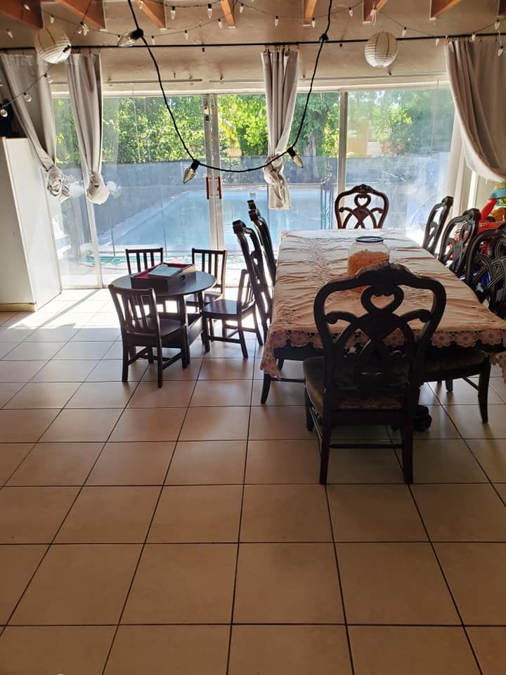 Dining room with two tables, one set for a meal. A pool can be seen outside.