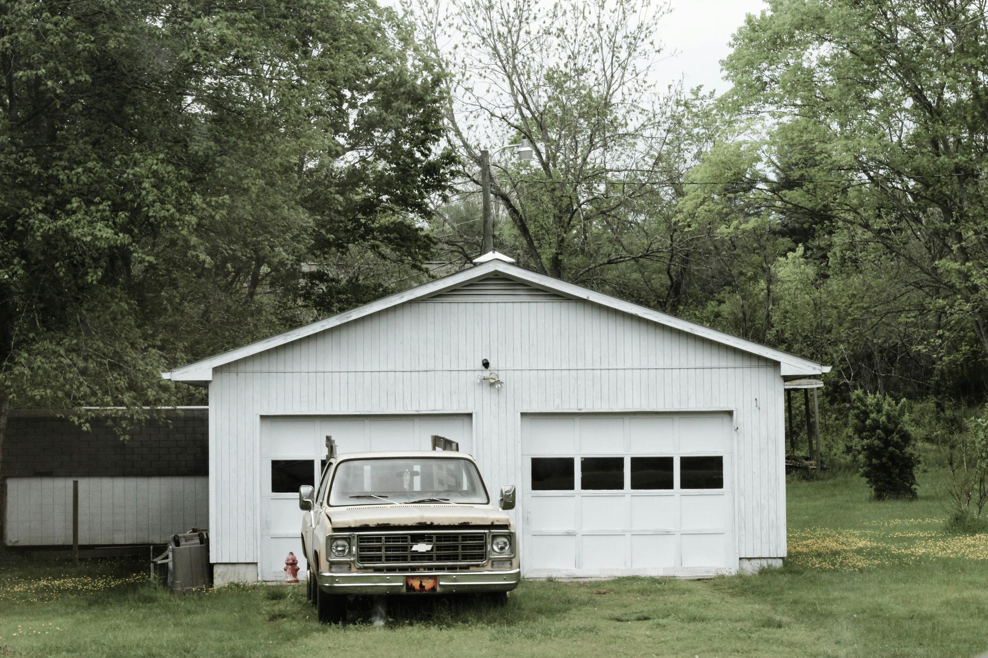 A garage with a black door is surrounded by trees.