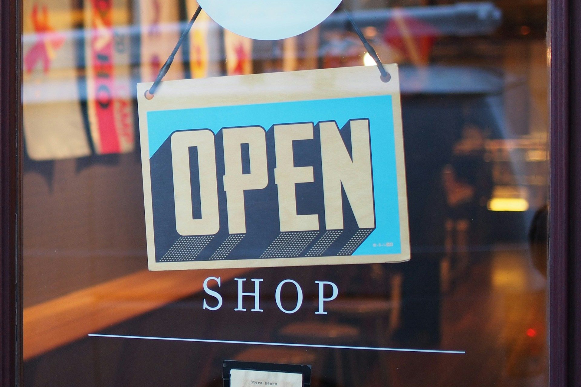 Open sign in a shop window, blue and tan colors, with shadow effect.