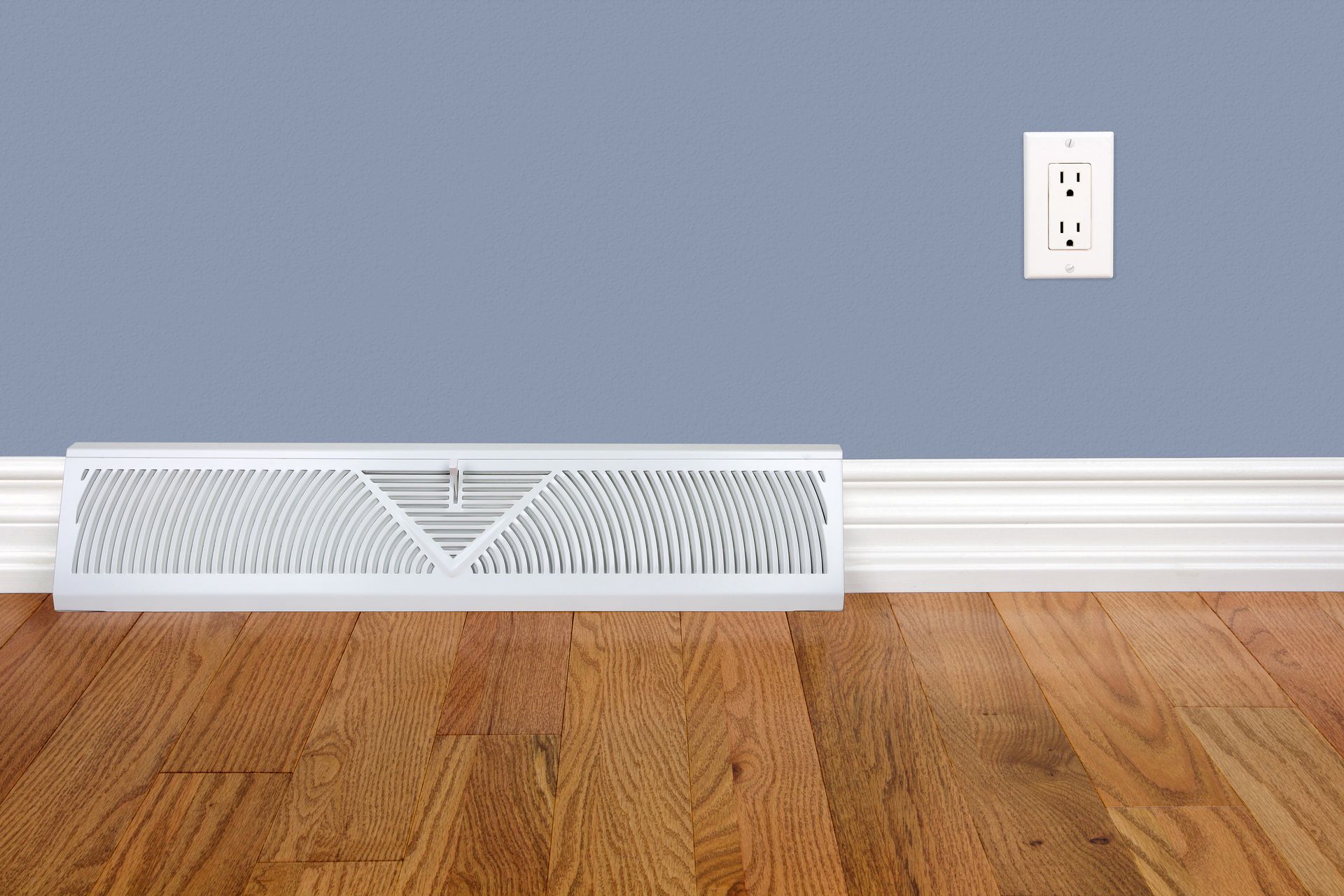 An empty room with hardwood floors and a white vent on the floor.