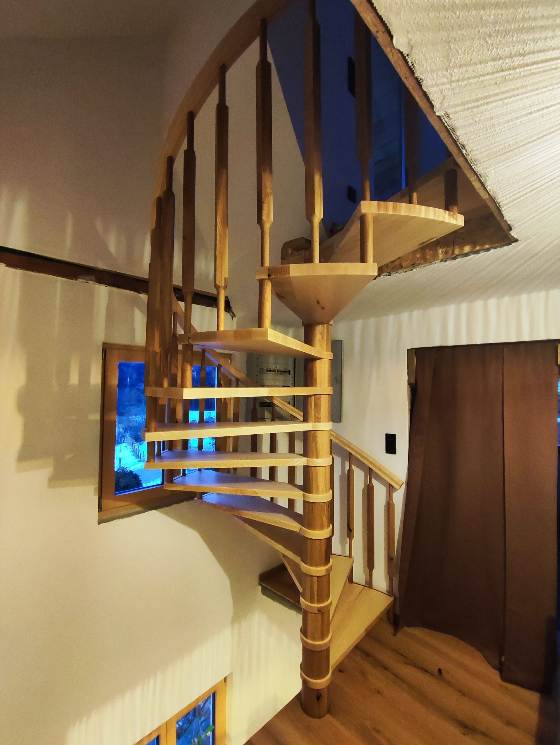 Eine hölzerne Wendeltreppe in einem Raum mit einem Fenster