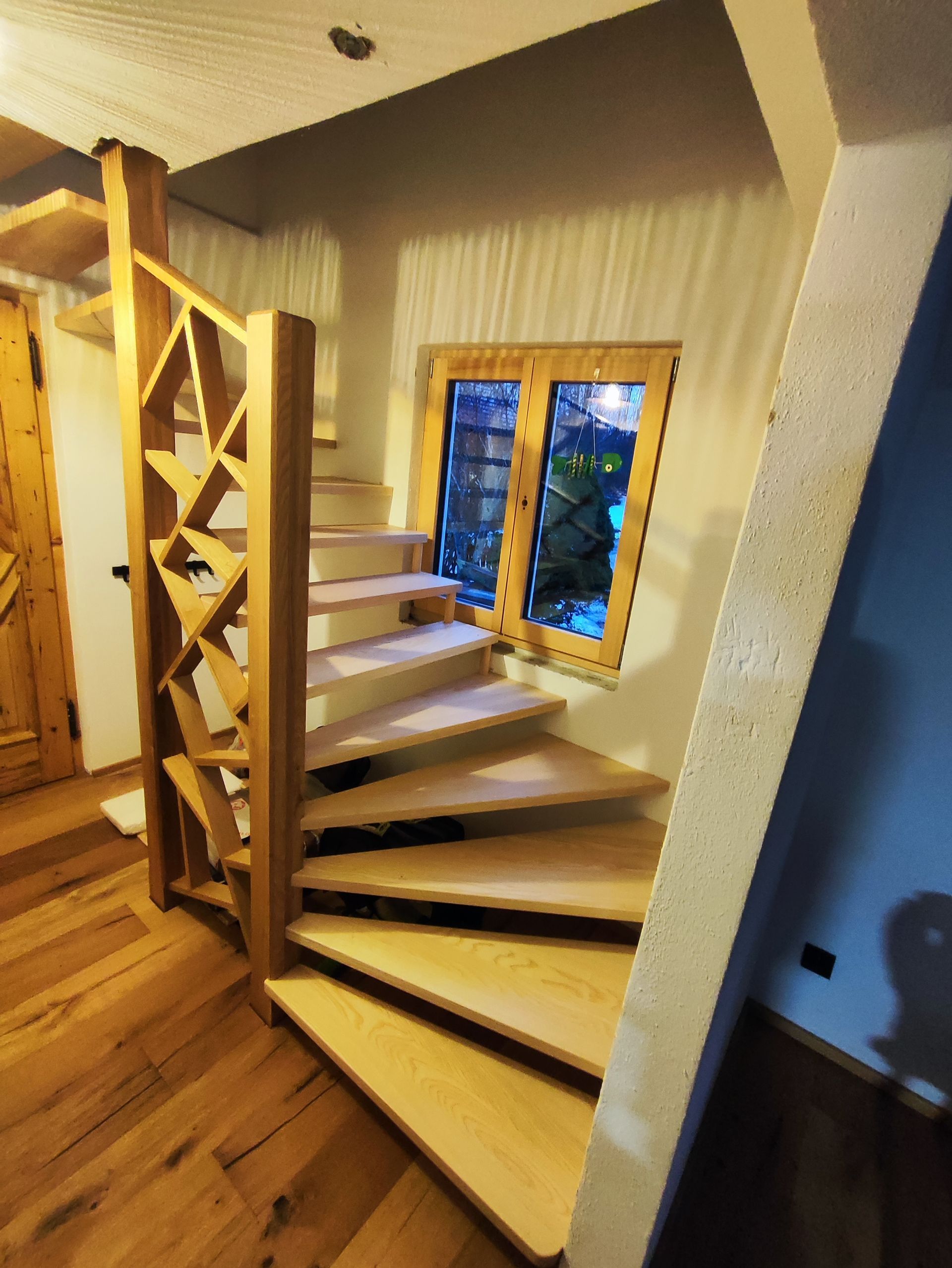 Eine hölzerne Wendeltreppe mit einem Fenster im Hintergrund