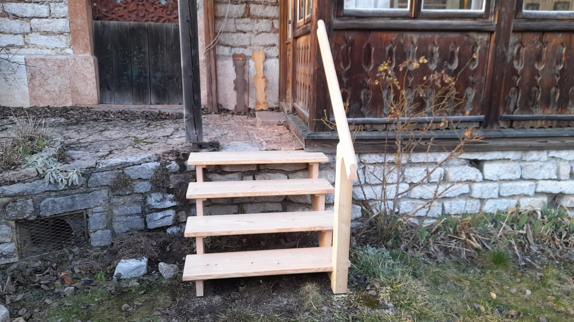 Eine Holztreppe führt zu einem Backsteingebäude hinauf.