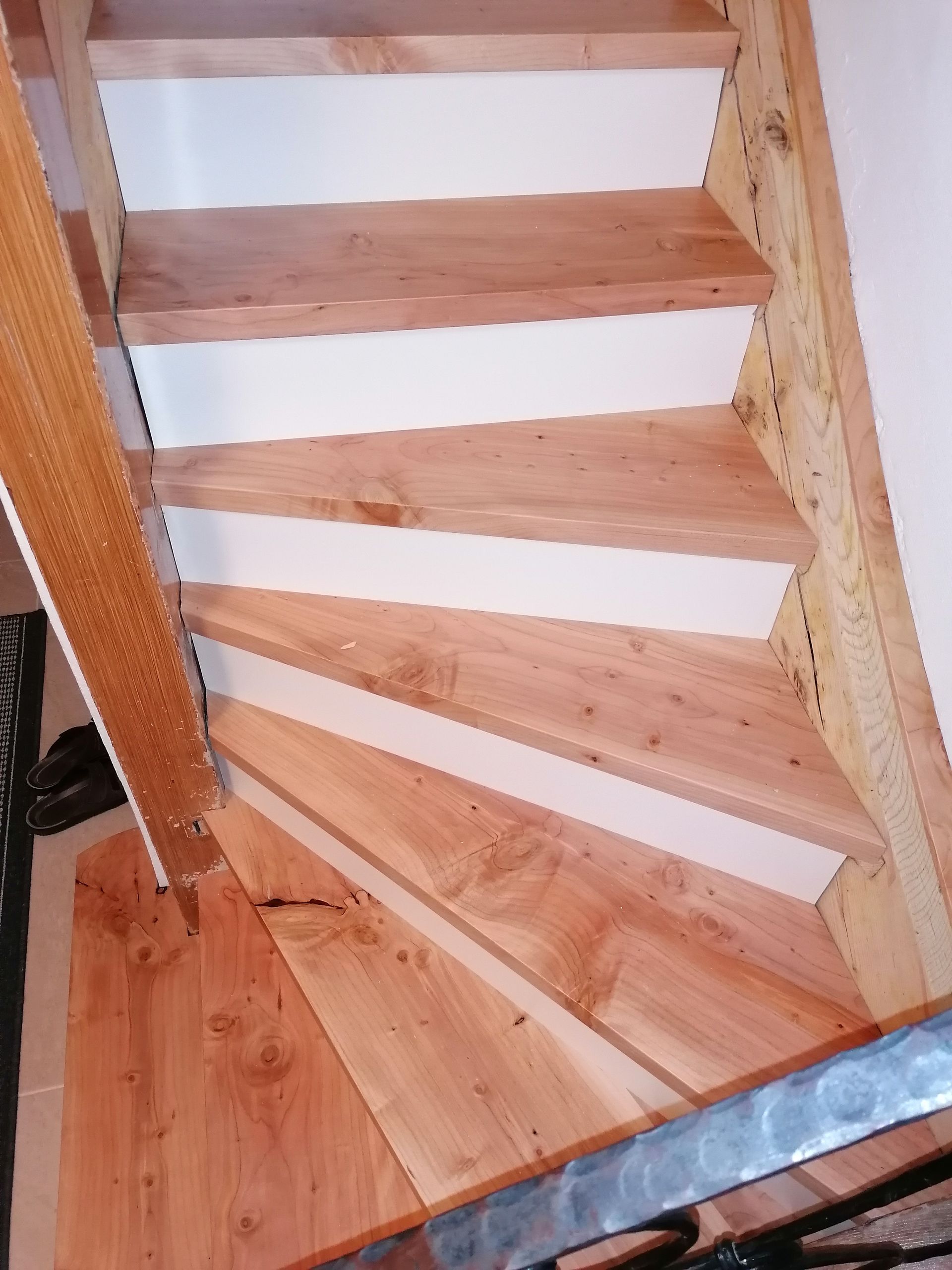 Eine hölzerne Wendeltreppe mit weißen Stufen und einem Metallgeländer