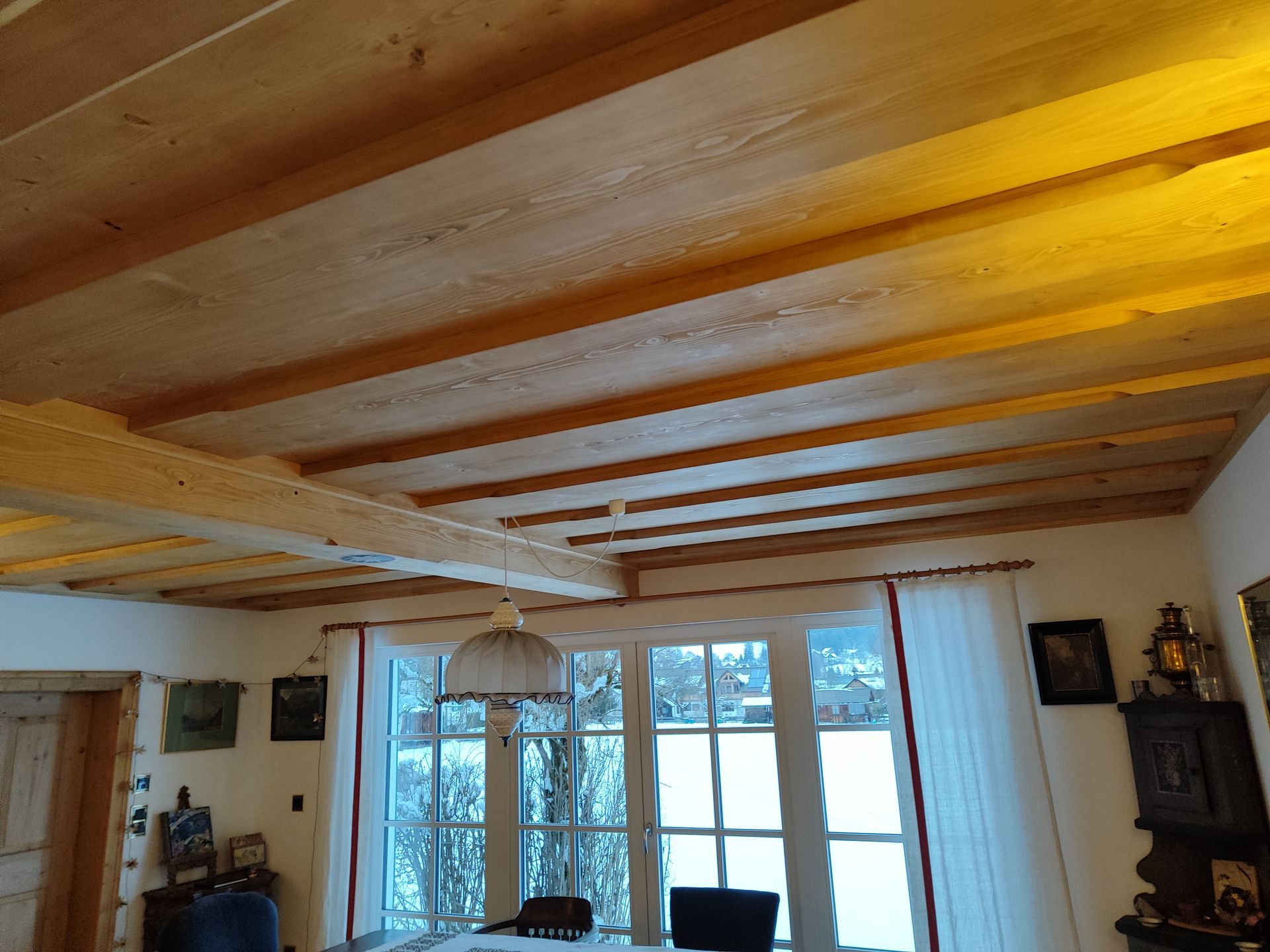 Ein Wohnzimmer mit Holzdecke und großem Fenster