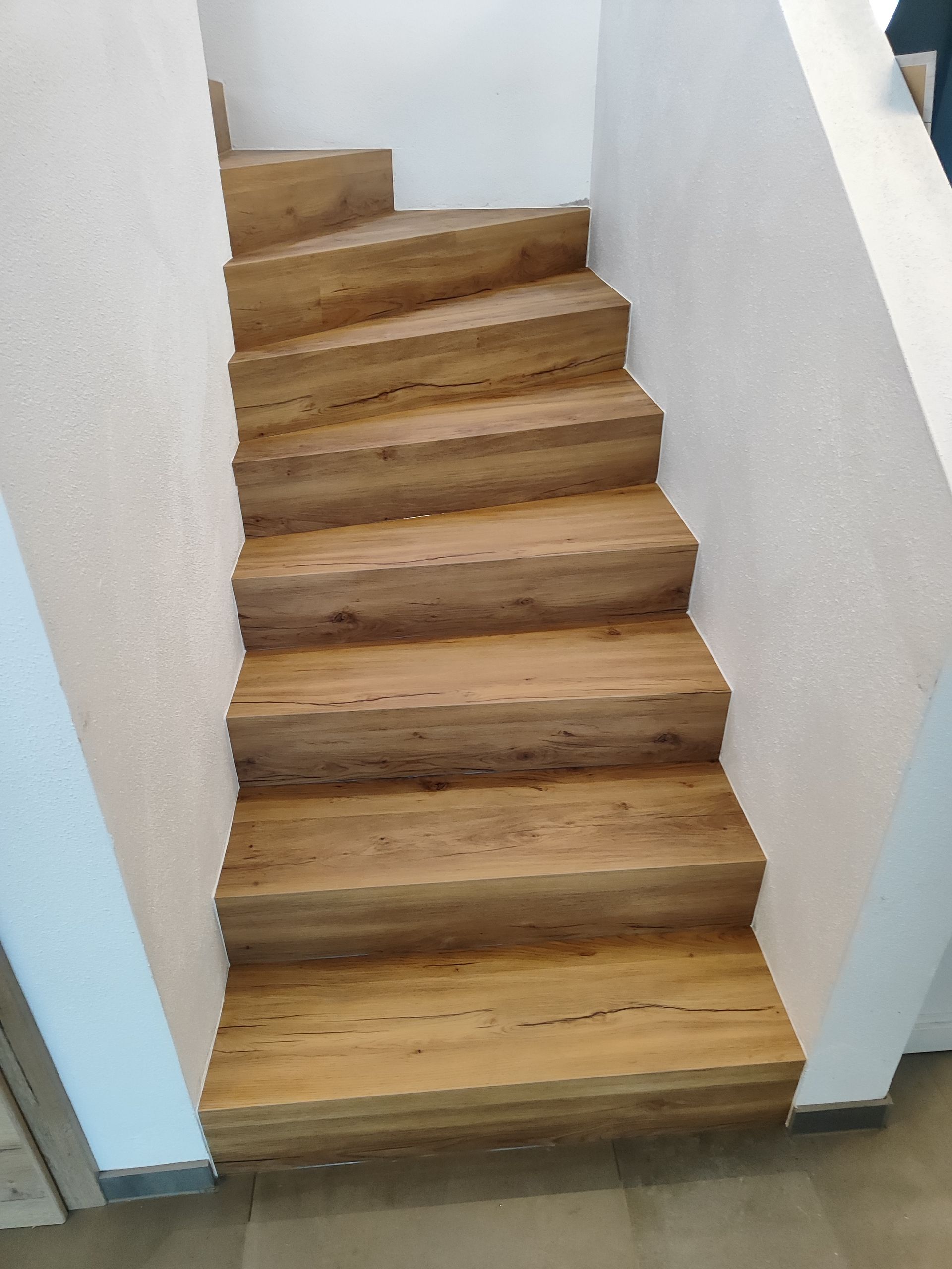 Eine Holztreppe in einem Haus mit einer weißen Wand.