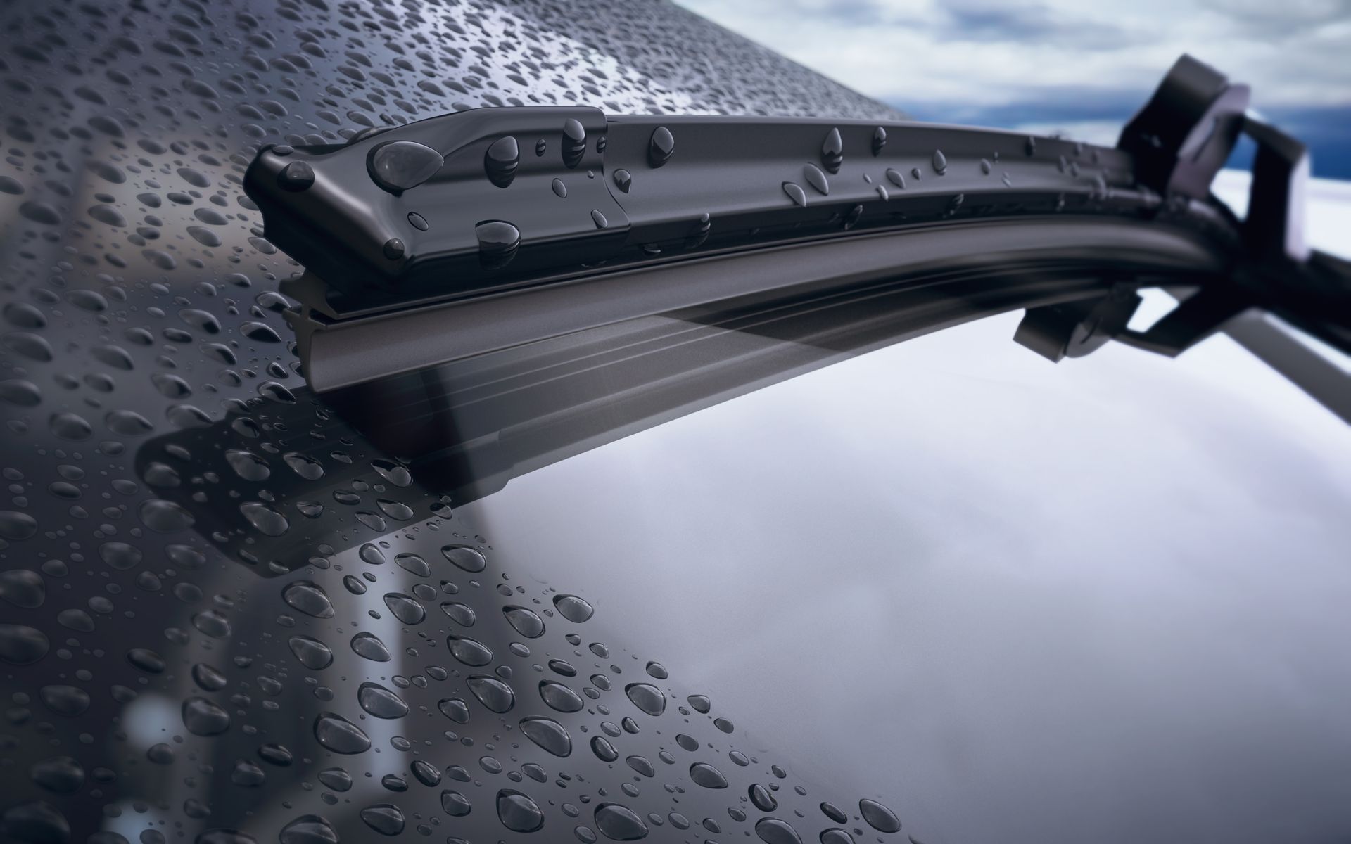 Black windshield wiper on a rain-covered car windshield, clearing water droplets