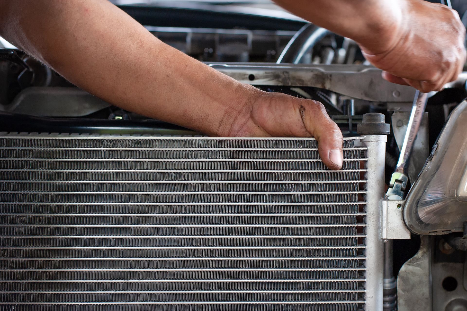 Hands adjusting a car radiator in the engine bay