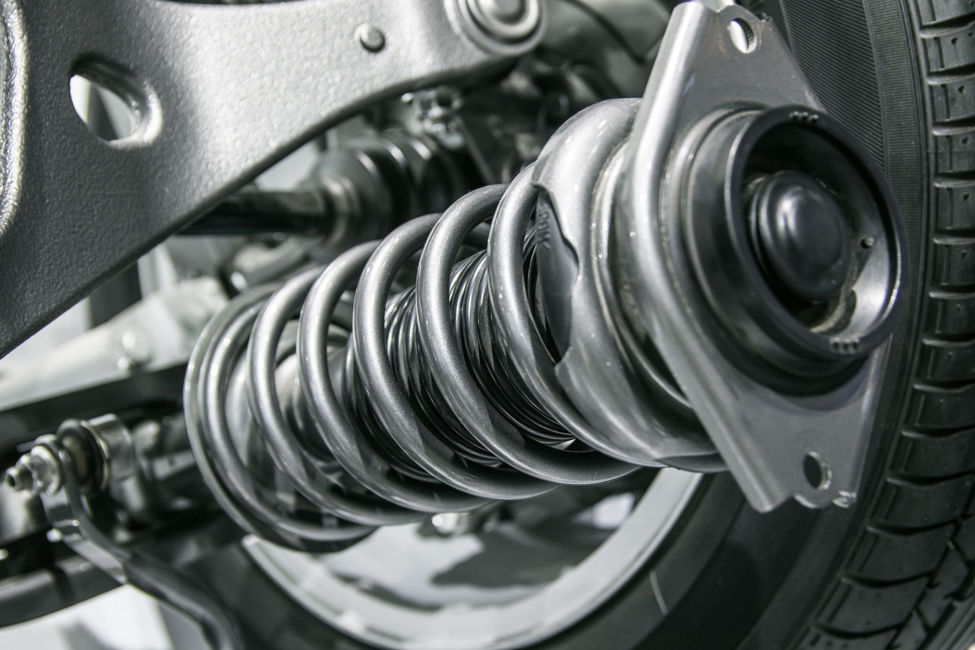 Close-up of a car suspension coil spring and wheel assembly in metallic silver