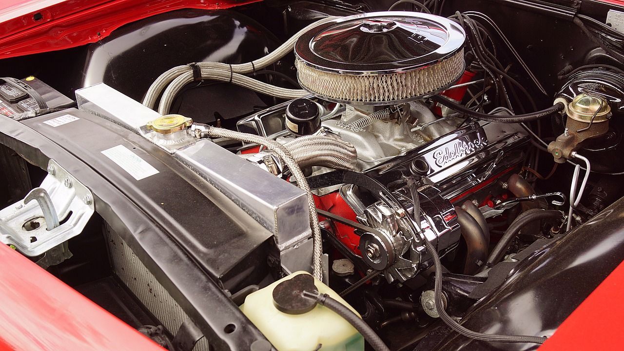 Polished car engine bay with chrome air filter and red body panels