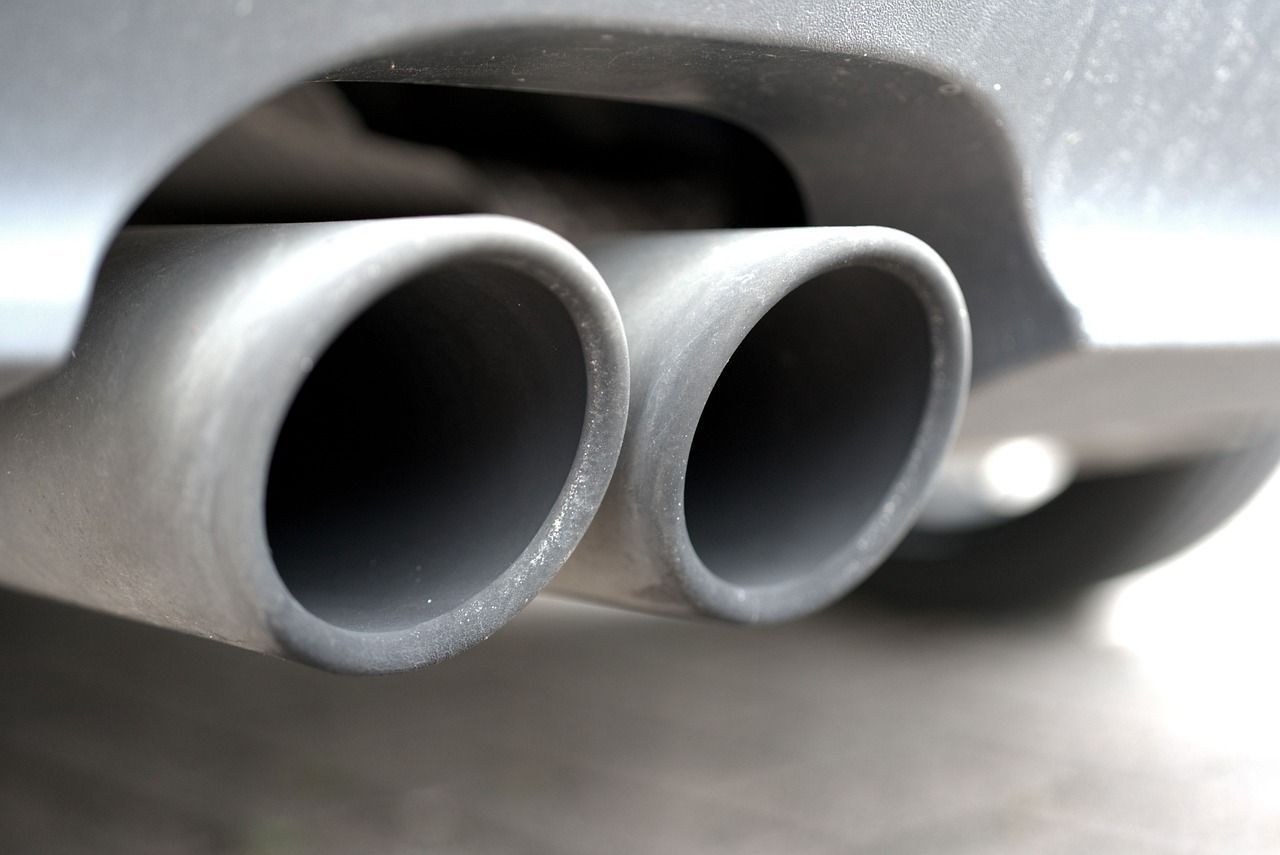 Close-up of two silver car exhaust pipes on a gray bumper