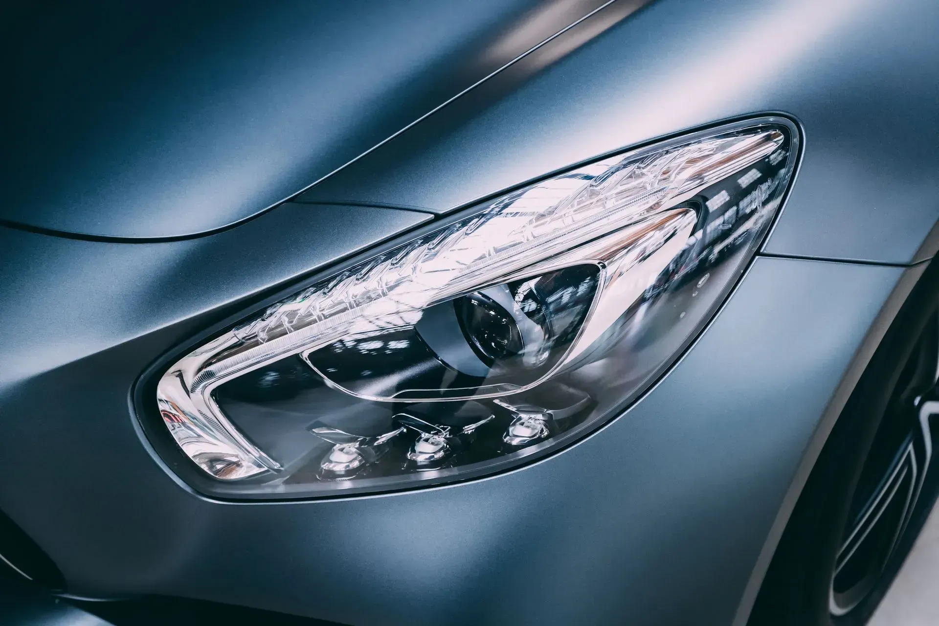 Close-up of a sleek silver car headlight on a dark metallic body
