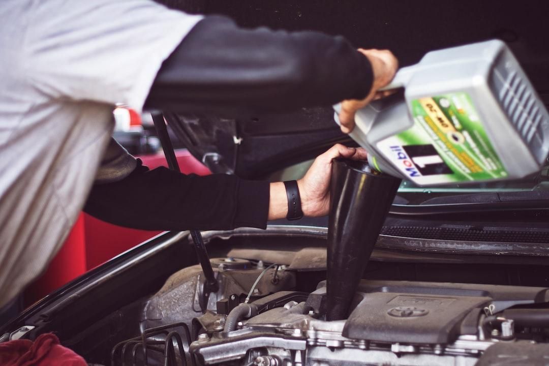 Person pouring motor oil into a car engine with the hood open