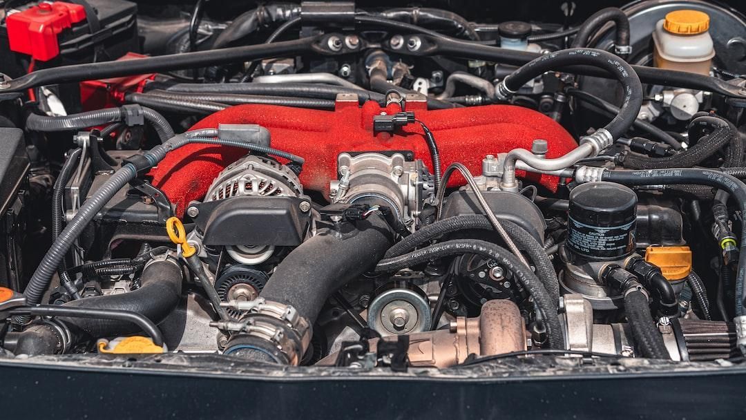Close-up of a car engine bay with red engine covers and black hoses.