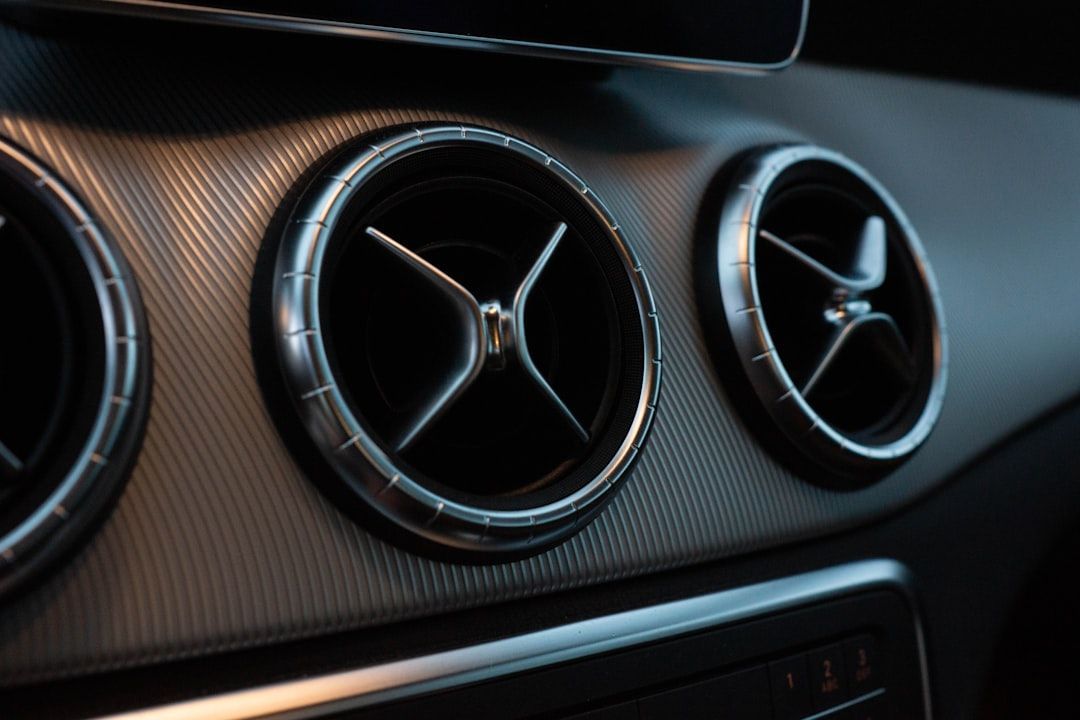 Close-up of a car dashboard with three circular air vents and brushed-metal trim