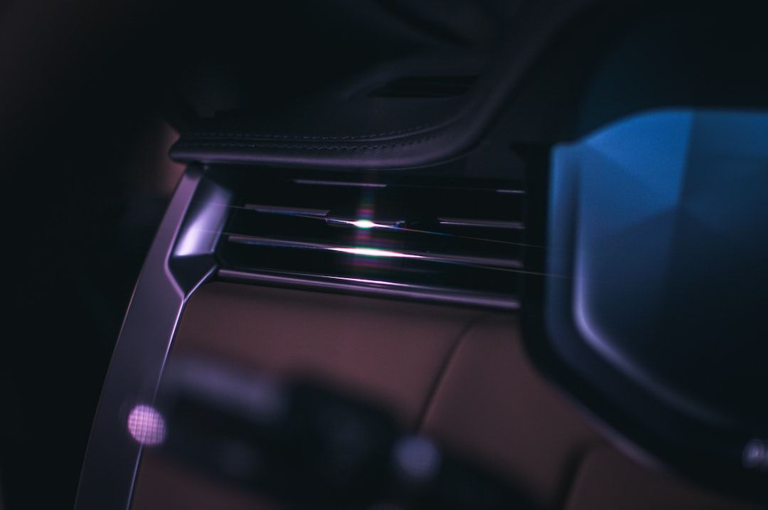 Close-up of a car dashboard vent with dark interior and blue-purple lighting