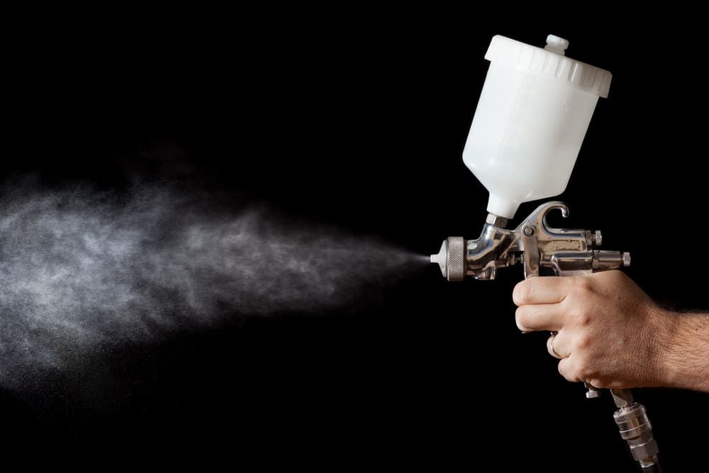 A Man Operates A Spray Gun, Releasing A Fine Mist Of Paint — Ballina Painting Service In Byron Bay, NSW