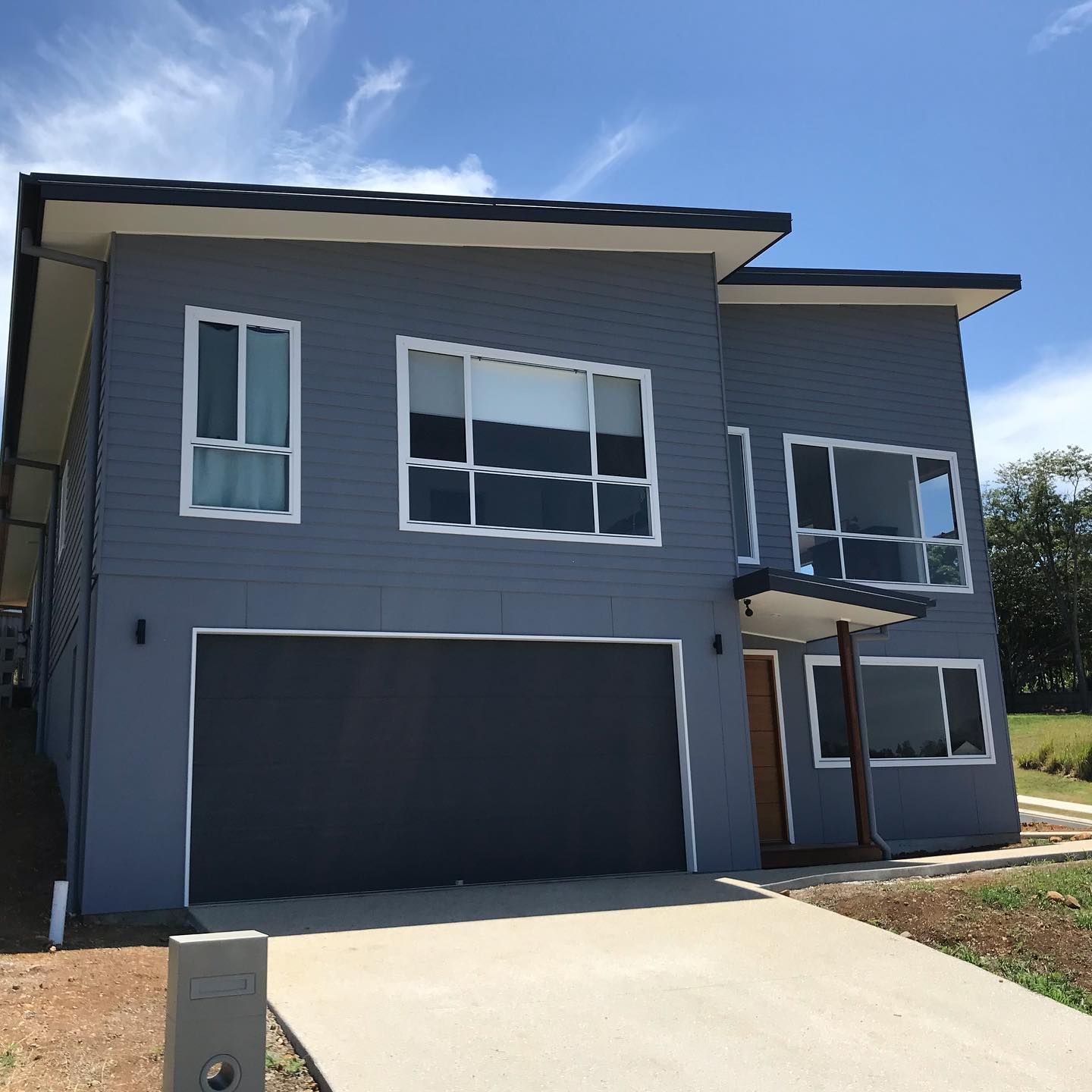 A Large Gray House With A Black Garage Door — Ballina Painting Service In Ballina, NSW