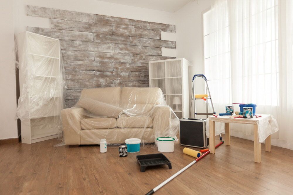 A Living Room Is Being Painted With A Couch Covered In Plastic — Ballina Painting Service In Bangalow, NSW