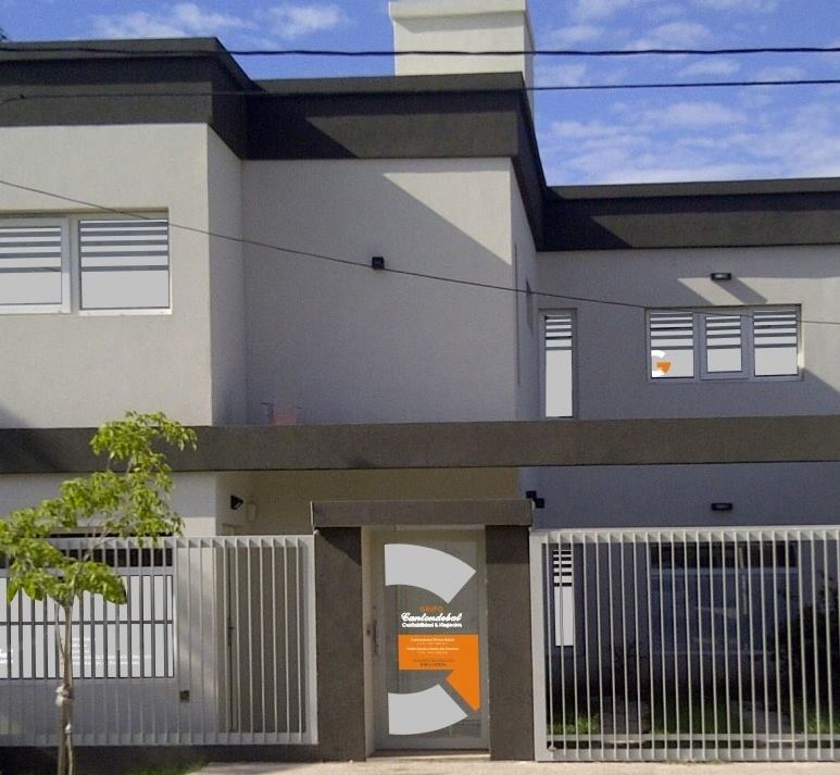 Edificio de dos plantas con paredes grises, molduras oscuras y un logotipo sobre la entrada