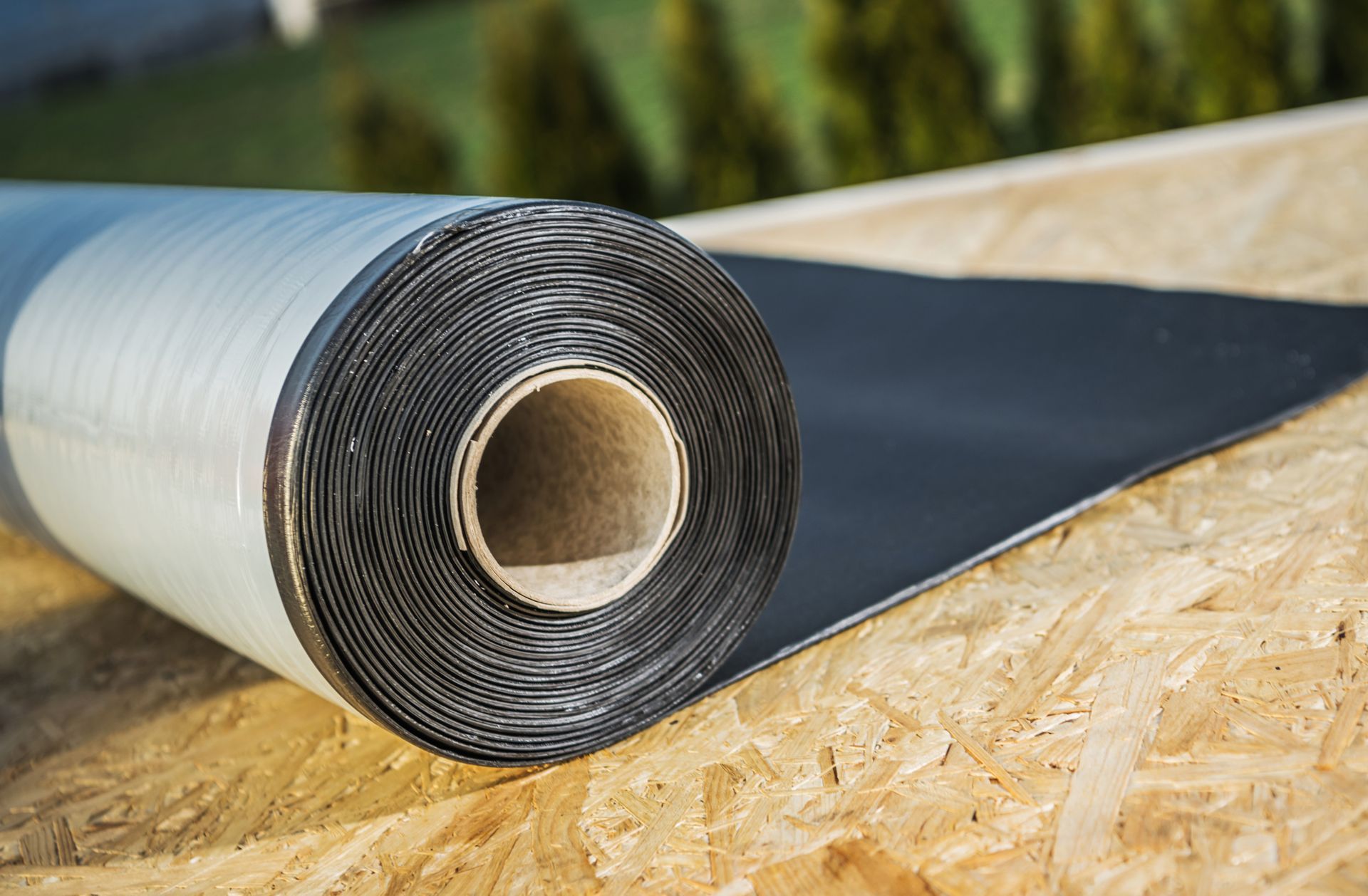 Roll of black roofing underlayment on wooden surface.