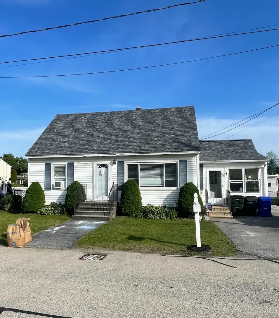 A man is standing on a ladder cleaning leaves from a gutter.