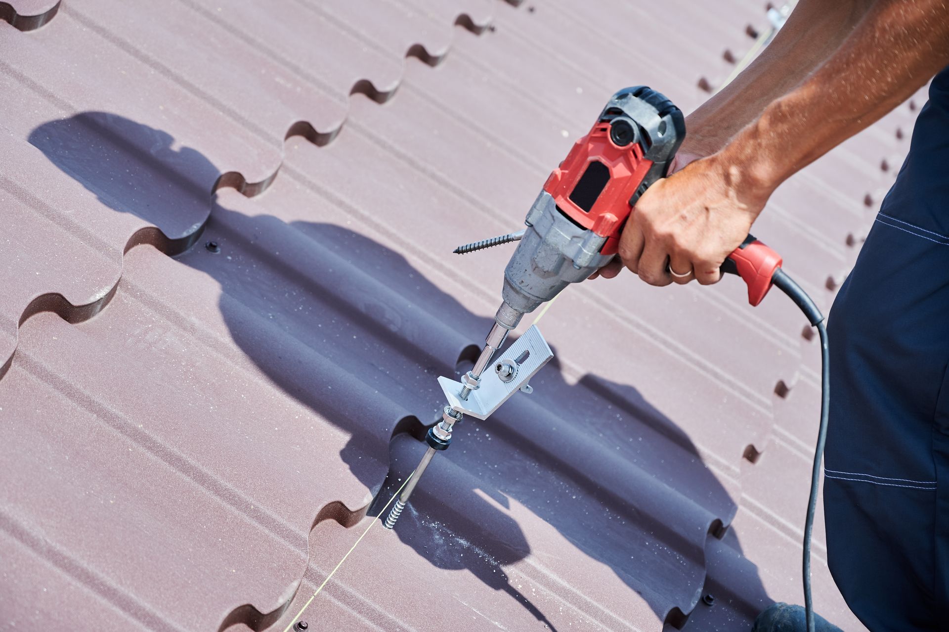 A man is using a drill to fix a roof.