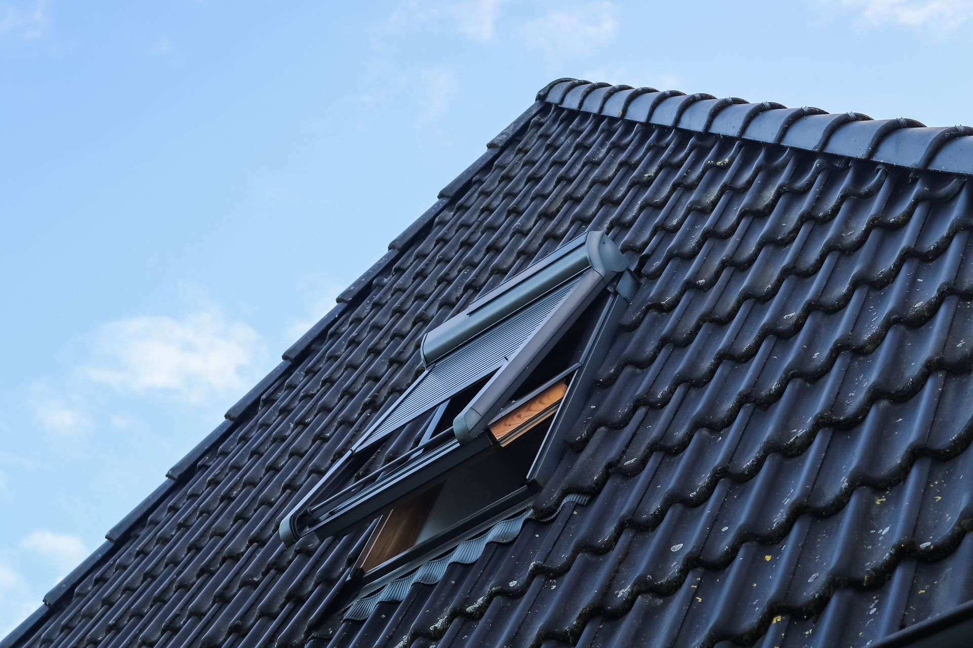 A roof with a window on it and a blue sky in the background