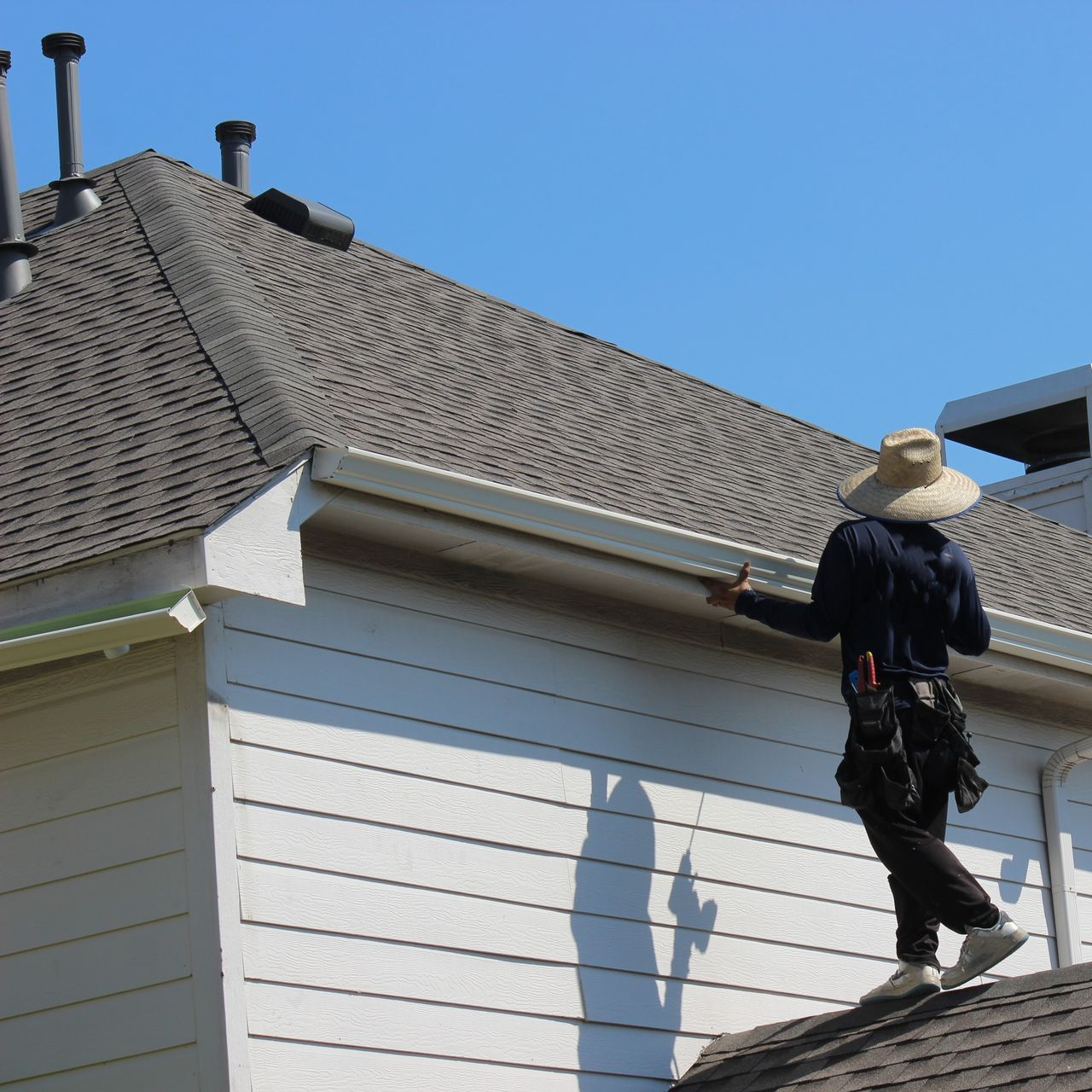 A man is working on the gutters of a house.